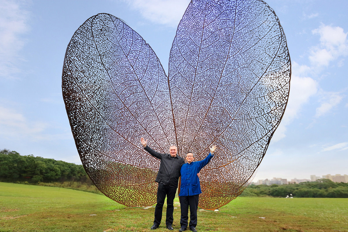 西班牙藝術家諾維亞(左)與賀陳弘校長(右)在像翅膀又像愛心的葉子前合影