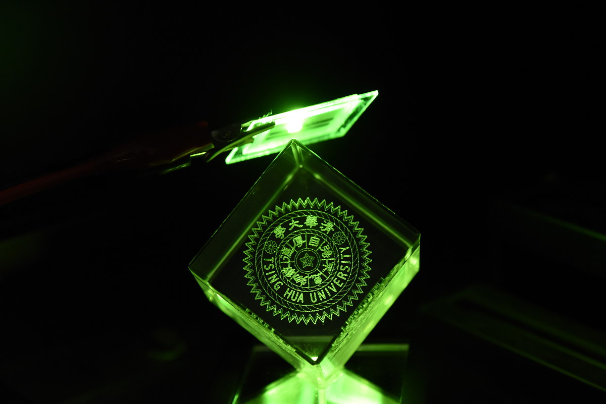 清華團隊開發雙硼材料高效能OLED元件，放出綠光照亮清華校徽。此照片刊登於自然光電期刊中