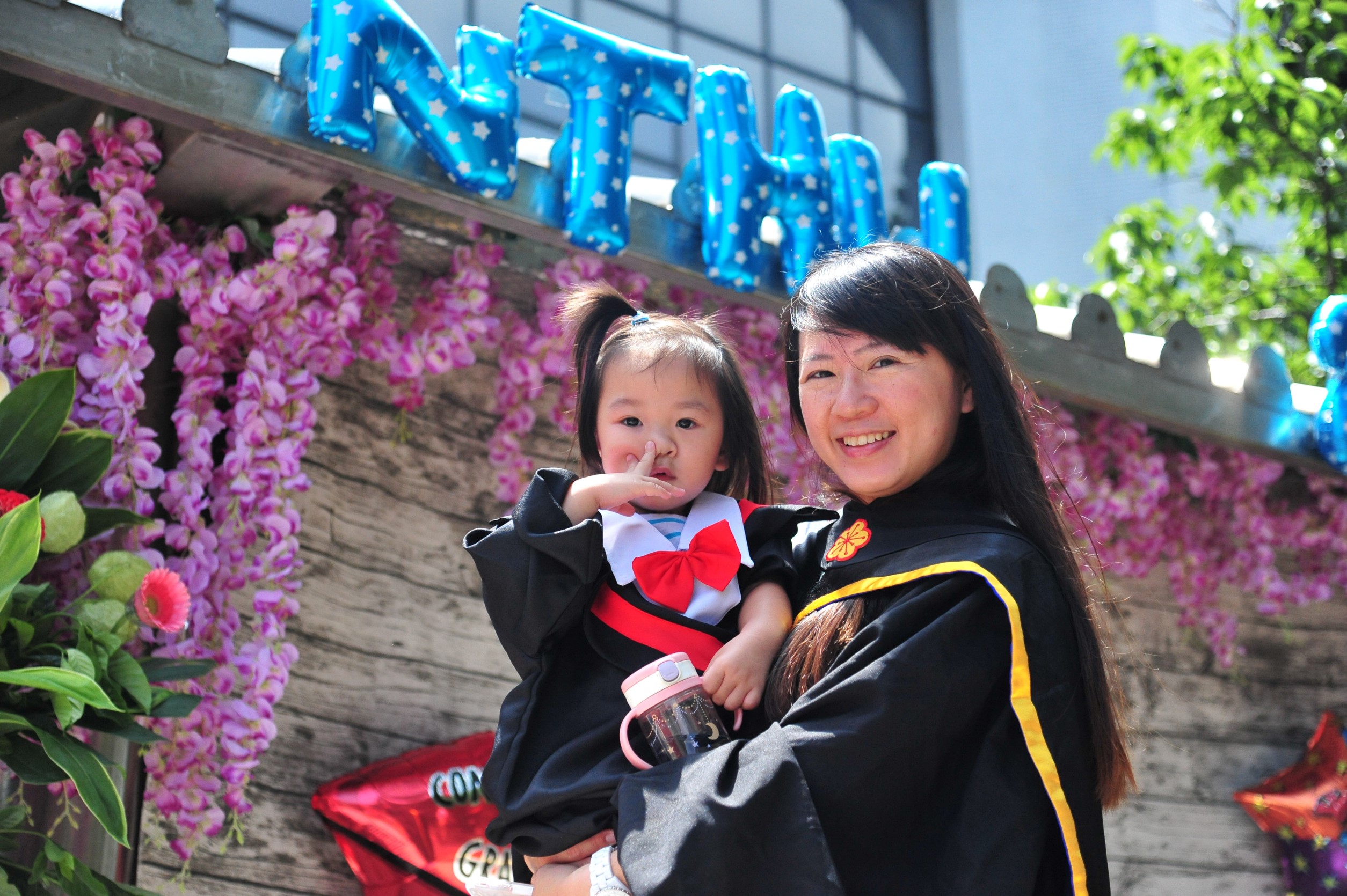 清華心諮所碩士生林怡秀抱著穿著畢業袍的女兒參加畢業典禮。