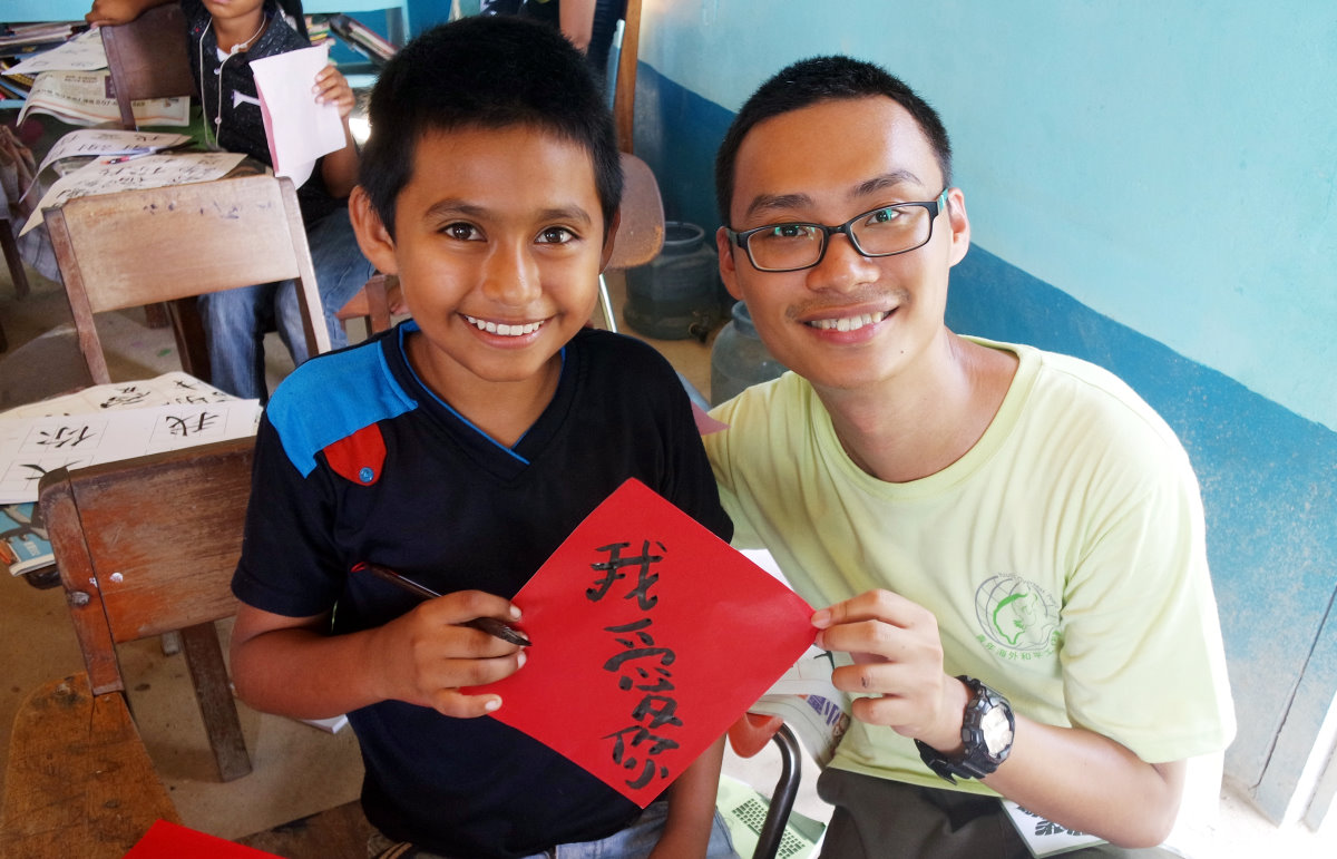 本校志工黃正太(右)教導貝里斯孩童書寫中文字