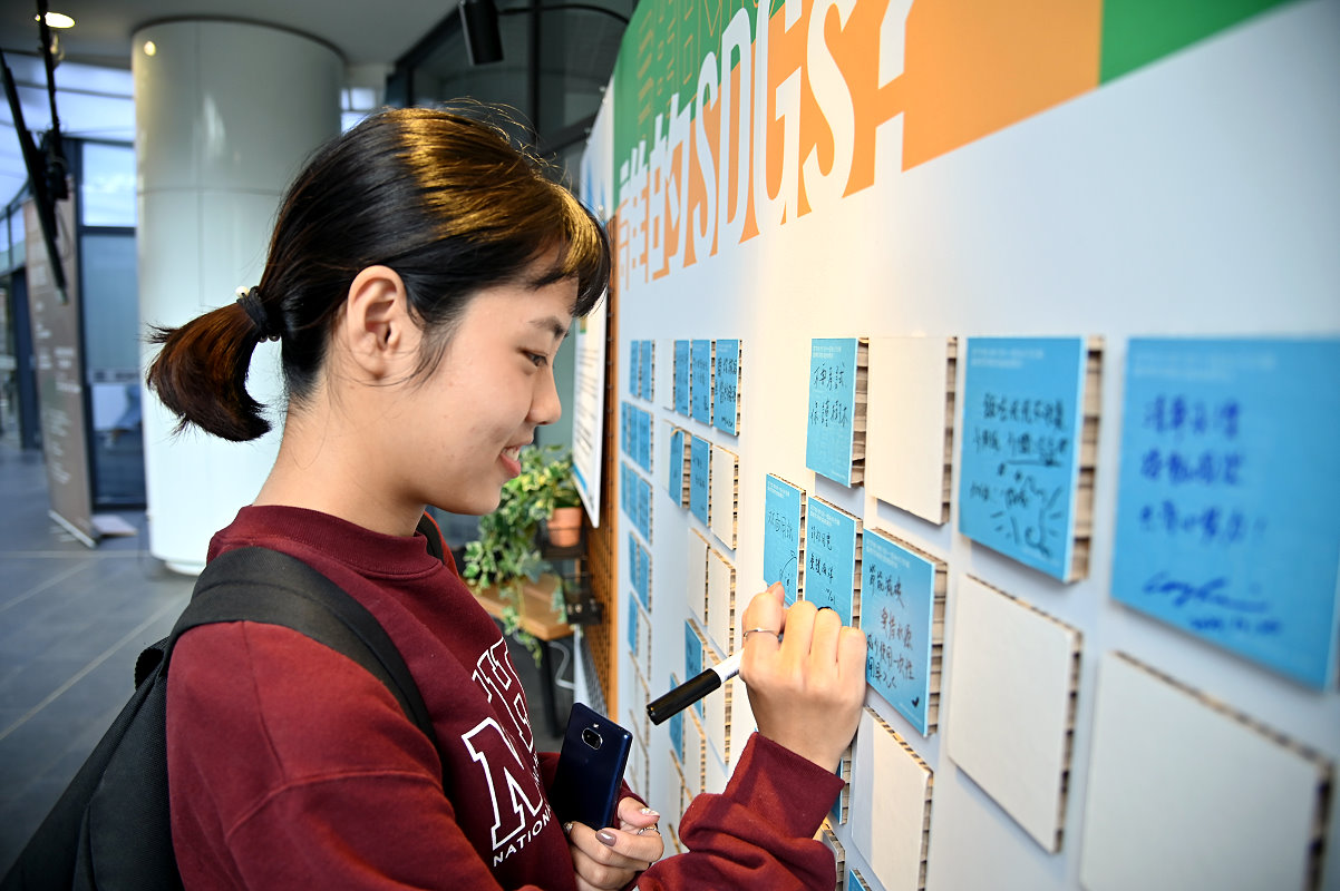 本校學生在旺宏館一樓的種子計畫牆寫下實踐永續的目標