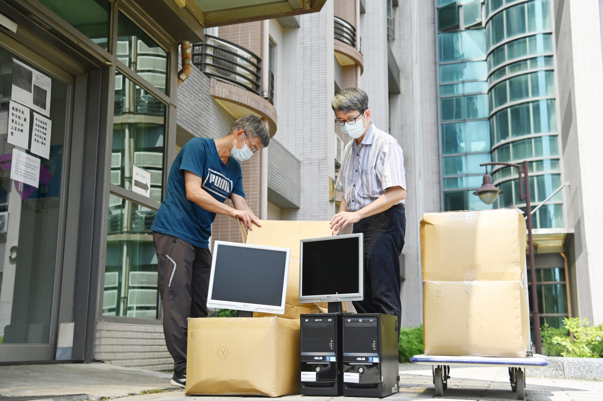 清華大學學務長王俊程（右）端午節前幫忙打包及搬運要送給建功中學弱勢生的電腦