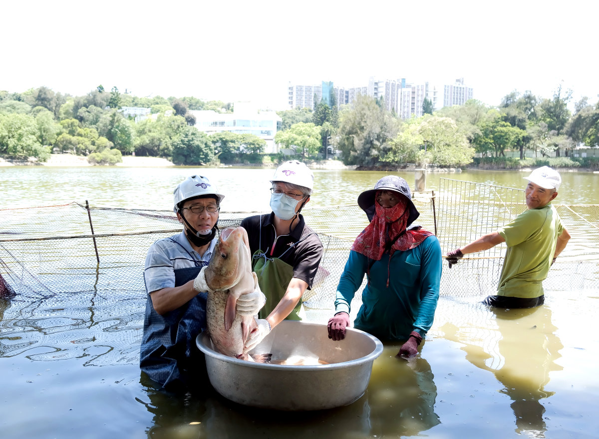 顏東勇總務長(左一)捧著魚頭跟人頭一樣大的大頭鰱