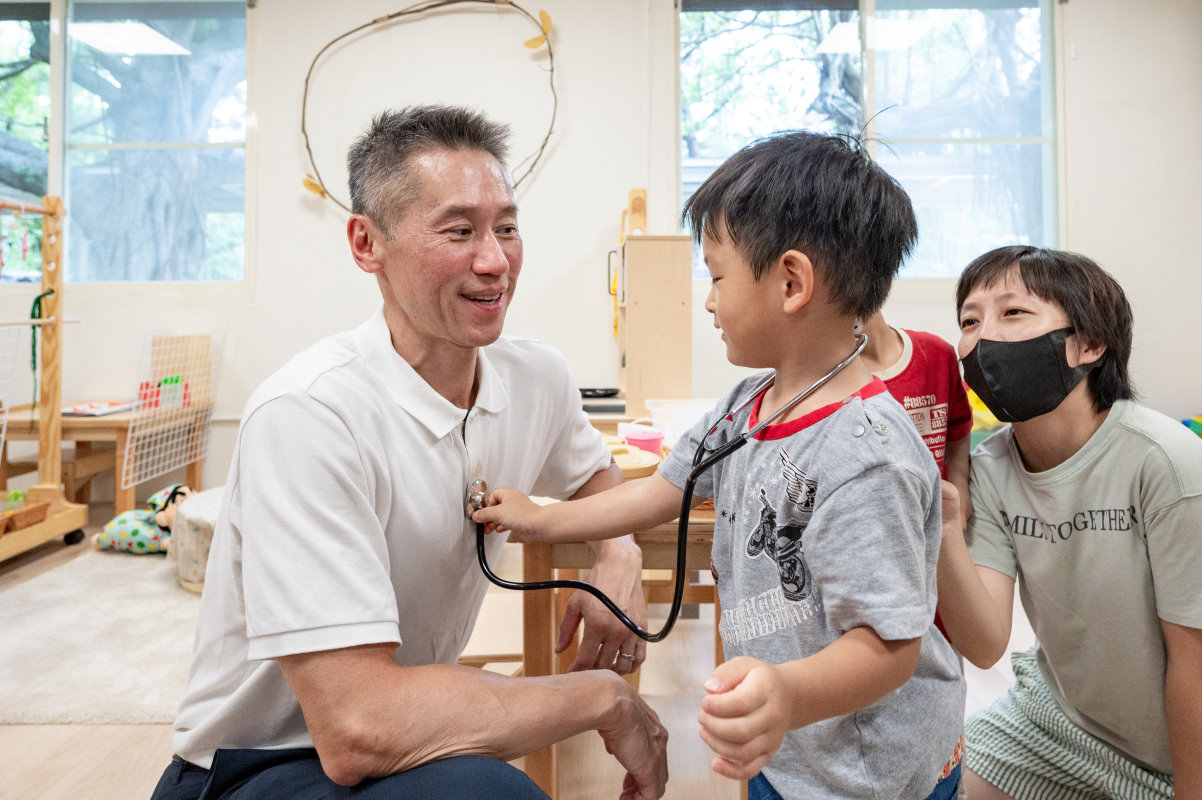 小朋友開心地扮起醫生，把聽診器貼在高為元校長胸前為他「看診」