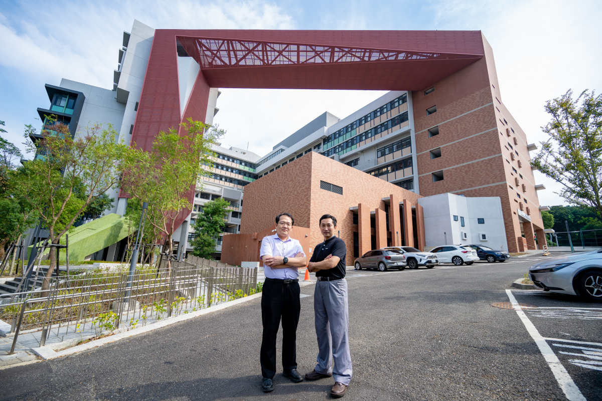 竹師教育學院王子華院長(左)與王淳民副院長(右)在新大樓前合影，背後紅色橫樑象徵「弘道之門」，寓意師道傳承